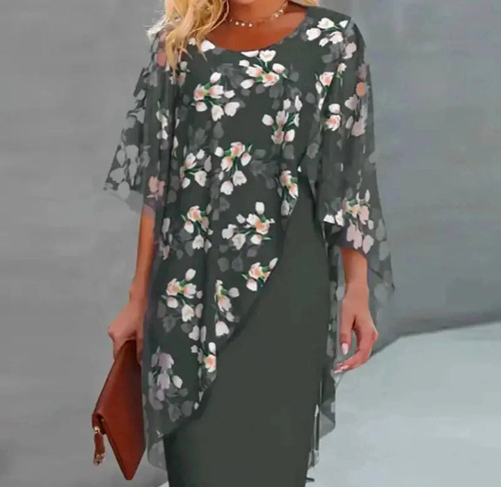 Green flowy cape dress with floral overlay, perfect for summer. Made of soft and breathable fabric for a comfortable and…