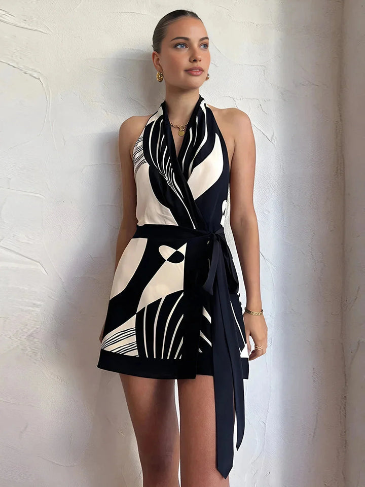 Abstract wrap dress with halter neck, sleeveless design. Made of lightweight fabric with unique pattern.