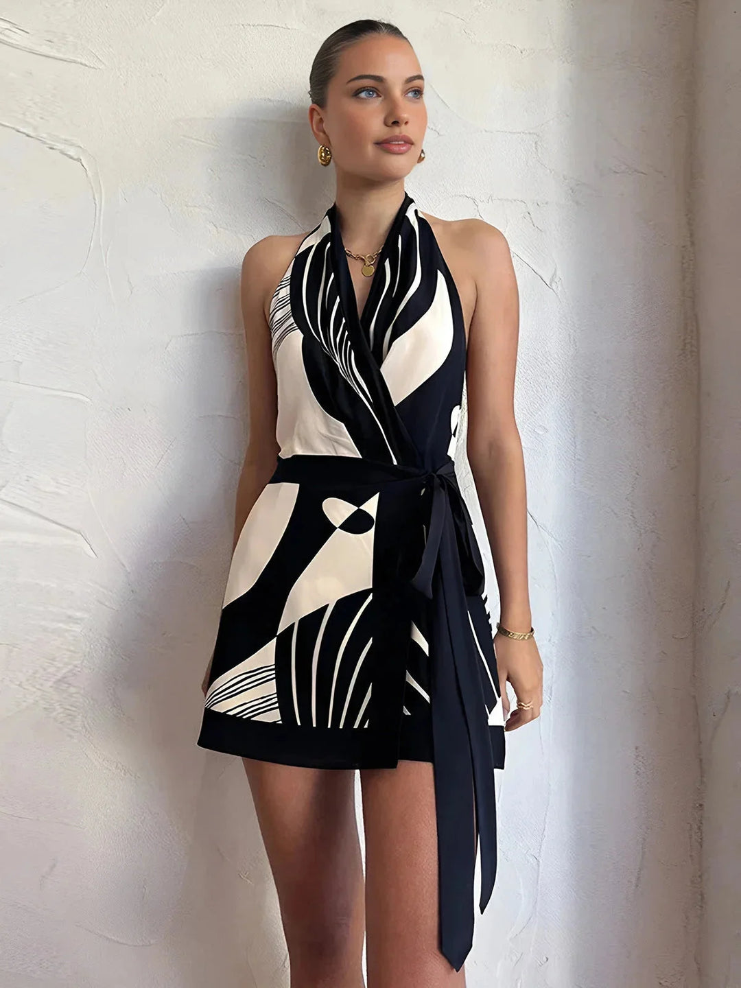 "Sleeveless wrap dress in black and white abstract pattern with halter neck, perfect for any occasion"