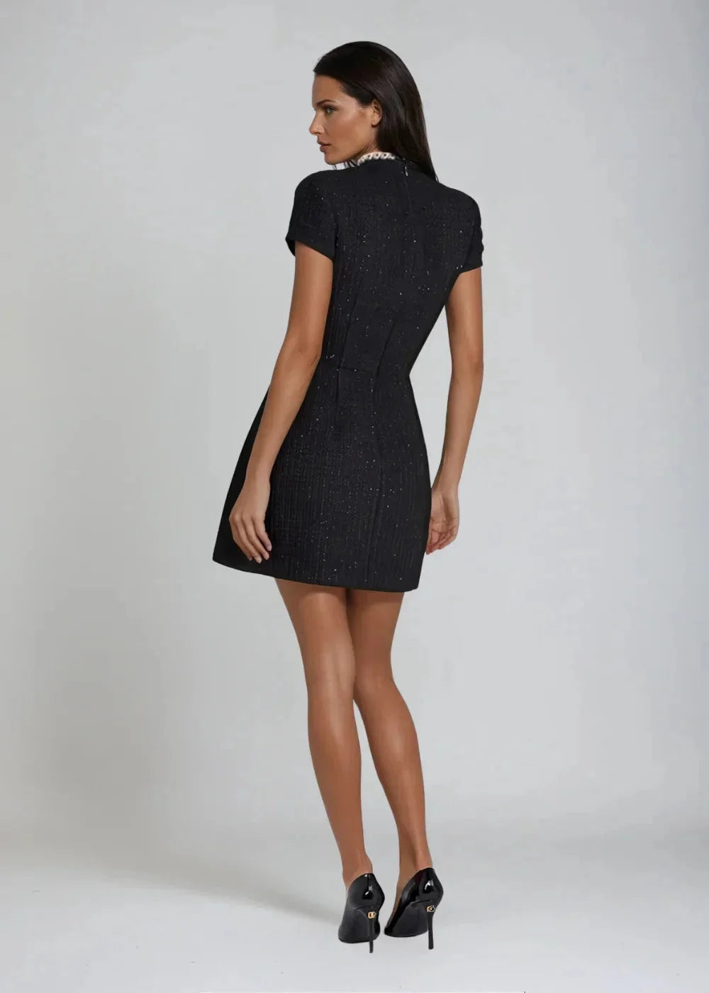 Black mini dress with mock neck and beaded trim details. Features a figure-hugging silhouette perfect for a night out.